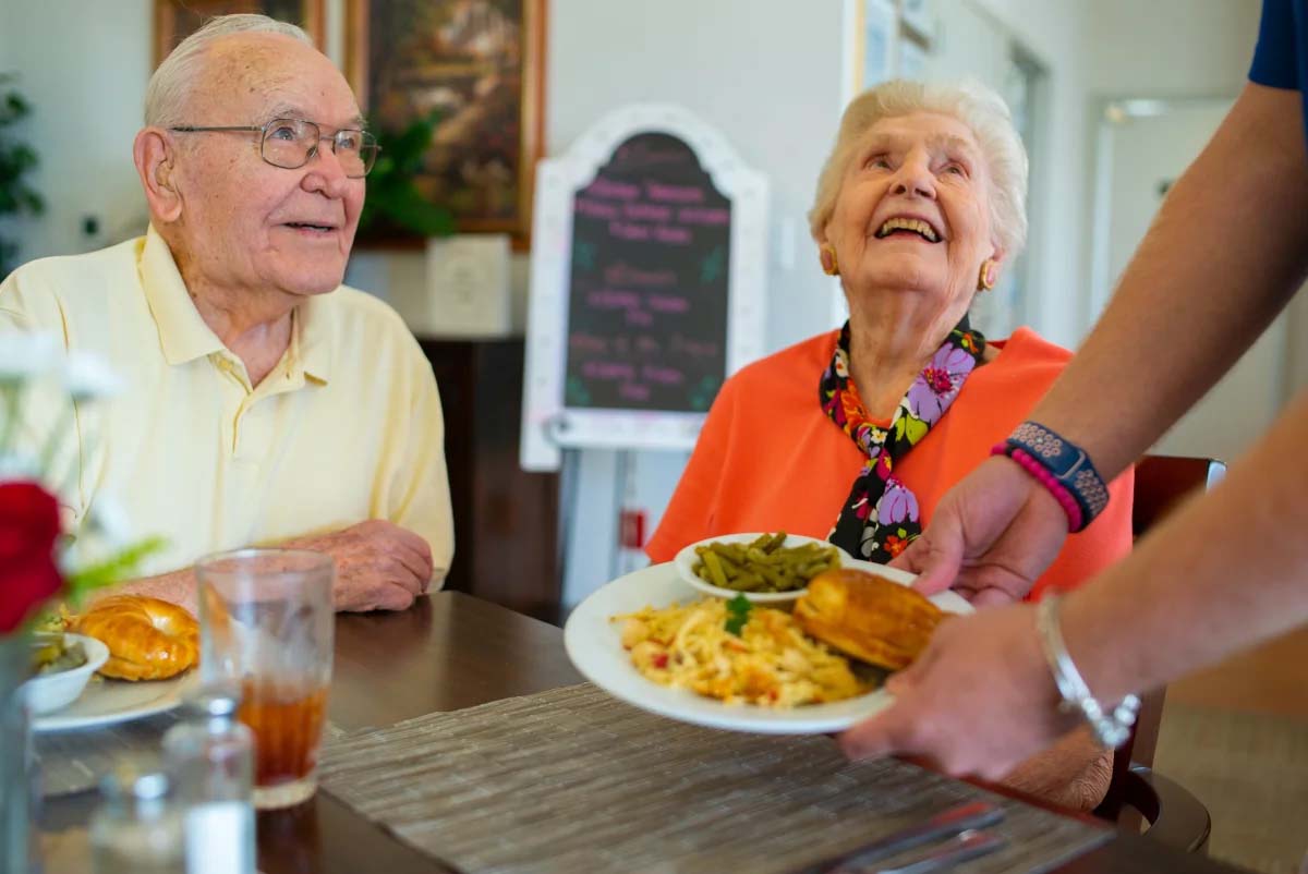 Elderly couple enjoying a meal in a restaurant setting.